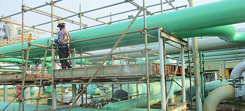 Pemandangan lokasi konstruksi industri di Cilegon dengan pipa besar dan scaffolding, menunjukkan proyek civil dan mechanical PT Cilegon Citra Pratama.