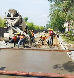 Pekerja konstruksi PT Cilegon Citra Pratama sedang melakukan pengecoran jalan dengan truk mixer di proyek konstruksi jalan Cilegon.